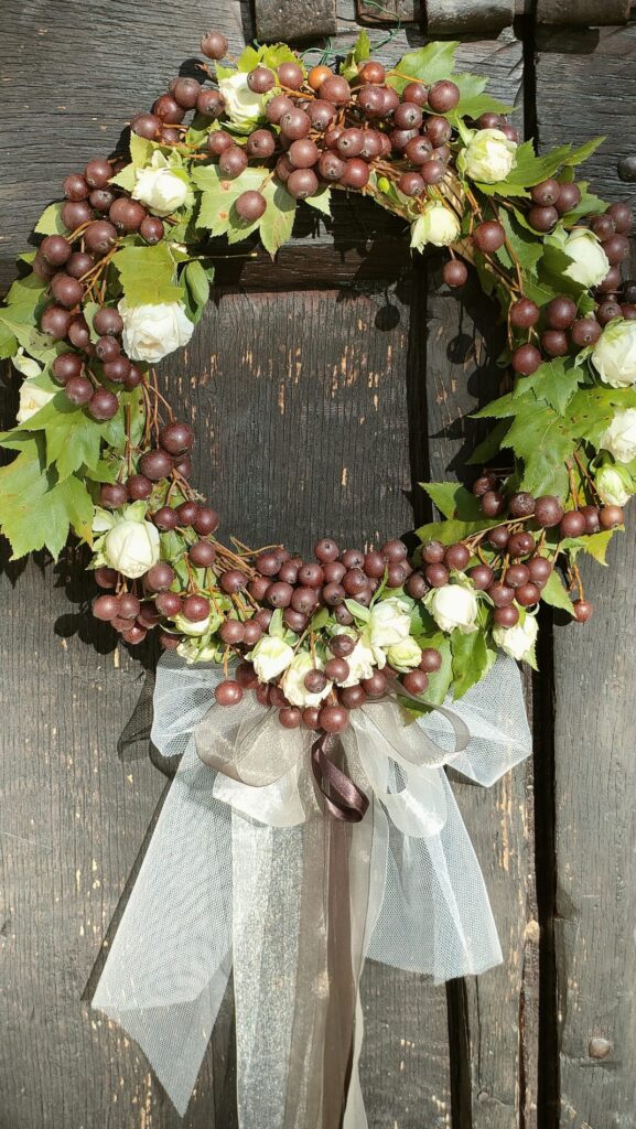 L'Arte delle Ghirlande Autunnali in questa bellissima ghirlanda di bacche violette e rose bianche